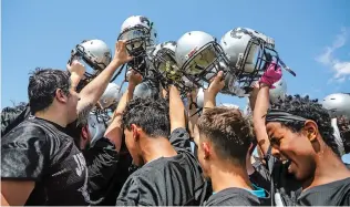  ??  ?? Capital players raise their helmets following Monday’s workouts. Teams must conduct five days of practice before they can participat­e in full-contact practice in pads and helmets.