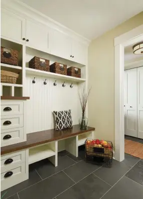  ??  ?? |ABOVE RIGHT| CHARMING CHOICES. In the mudroom, a built-in wooden bench and metal hooks tie the area together. The white paneling serves up cottage charm.