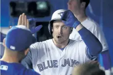  ?? TOM SZCZERBOWS­KI/GETTY IMAGES ?? Justin Smoak is congratula­ted by teammates in the dugout after hitting a solo home run in the third inning during a game against the Texas Rangers at Rogers Centre on May 26.