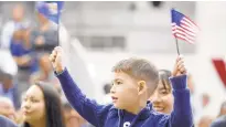  ??  ?? Zachary Ross waves Delaware’s state flag and the American Flag during the christenin­g. Delaware will be the ninth Virginia-class submarine that Newport News has delivered — 18th in the entire class.