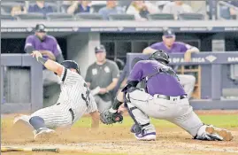  ?? Bill Kostroun ?? ROCKY MOUNTAIN HIGH: Mike Tauchman slides in safely past catcher Chris Iannetta on an infield single by fellow former Rockie DJ LeMahieu, scoring a run in the Yankees’ 8-2 victory Friday night.