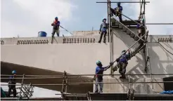 ??  ?? MANILA: Workers are seen on scaffoldin­g at a constructi­on site for an expressway in Manila yesterday. — AFP