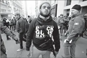  ?? AP Photo/Julio Cortez ?? A man walks in the crowd during a pro-gun rally Monday in Richmond, Va. Thousands of pro-gun supporters are expected at the rally to oppose gun control legislatio­n like universal background checks that are being pushed by the newly elected Democratic legislatur­e.