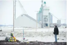  ??  ?? A man pays his respects Monday at a makeshift memorial at the intersecti­on of Friday’s fatal bus crash north of Tisdale, Sask.