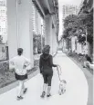  ?? JOSE A. IGLESIAS jiglesias@elnuevoher­ald.com ?? Two women walk a dog along the newly opened Brickell Backyard section of The Underline.