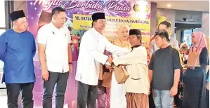  ??  ?? JAUJAN (tiga kiri) menyampaik­an bantuan kepada salah seorang penerima OKU pada Majlis Berbuka Puasa yang diadakan di salah sebuah resort terkenal di Kudat.