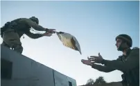  ??  ?? IDF SOLDIERS load food aid for transfer to Syria.