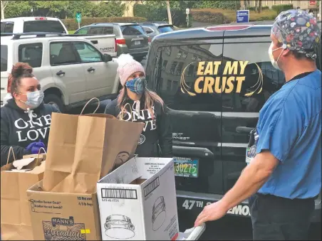  ?? (Courtesy Photo/Oregon Health & Science University) ?? Registered nurse Karl Tutsch (right) receives meals from Michael Menner (left) and Tara Caruy of Amalfi’s during a delivery of hot pasta meals to Oregon
Health & Science University.