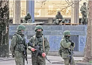  ?? Genya Savilov / AFP / Getty Images ?? Armed men patrol outside the Crimean Parliament on Saturday in Simferopol, where pro-Russian forces tightened their grip as the Kremlin vowed to help restore calm on the restive Ukrainian peninsula. Dozens of men in full combat gear were patrolling...