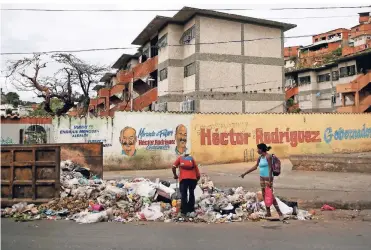  ?? FOTO: REUTERS ?? In der Krise: Auf den Straßen von Caracas suchen zwei Bürger im Abfall nach Lebensmitt­eln.