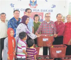  ??  ?? Ahmad Lai (third right) presents the essential items to a family at the function.