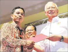  ??  ?? Najib presents the Village Governance Certificat­e to a JKKK representa­tive. At centre is Ismail Sabri.