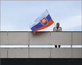  ?? Denes Erdos Associated Press ?? A MAN WAVES Slovakia’s f lag outside the F.D. Roosevelt University Hospital in Banska Bystrica, where Prime Minister Robert Fico was being treated.