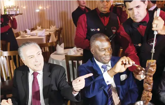  ??  ?? Brazilian President Michel Temer and Angola’s Ambassador Nelson Manuel Cosme eat barbecue in a steak house in Brasilia after a meeting with ambassador­s from countries that import Brazilian meat, on Sunday. (AFP)