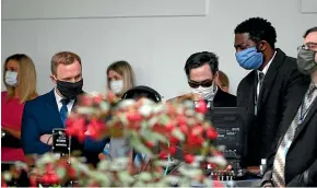  ?? AP ?? Staff members wear masks as they listen to President Donald Trump speak about the coronaviru­s during a press briefing in the Rose Garden of the White House.