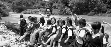  ??  ?? Dennis and students of SK Long Luteng pointing to the damaged suspension bridge connecting the village to the school.