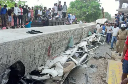  ?? PTI ?? People look at the vehicles crushed under the flyover at the collapse site in Varanasi on Wednesday, a day after the tragedy. —