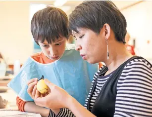  ??  ?? Annette Prapasiri helps her son, Fin Prapasiri, decorate his pysanky egg with an octopus during a recent egg demonstrat­ion at Southside Branch Library.