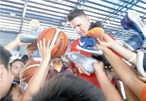  ?? SUNSTAR FOTO / MARIANNE L. SABERON-ABALAYAN ?? PLEASE SIGN. Towering National Basketball Associatio­n (NBA) basketball operations associate Cherokee Parks gamely signs autographs on participan­ts’ rubber shoes, basketball­s, tumblers and jerseys after a basketball clinic at the Ateneo de Davao University Senior High School gym in Bangkal, yesterday.