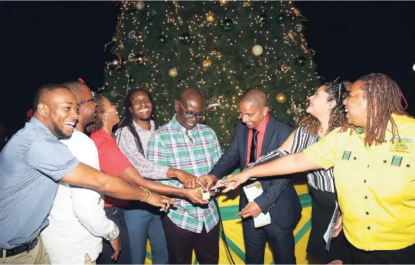  ?? HECTOR/PHOTOGRAPH­ER PHOTOS BY SHORN ?? Minister of Local Government and Community Developmen­t Desmond McKenzie (fourth right) and Mayor of Kingston Delroy Williams (third right) along with Alando Terrelonge (fourth left), state minister of culture, and others, flip the switch to turn on the lights on the Christmas tree at the St William Grant Park in Kingston on Thursday night. The group was participat­ing in the annual tree-lighting ceremony.