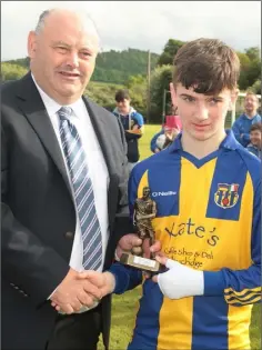  ??  ?? Don Hearne, Wexford and District Schoolboys League secretary, presents the Under-14 Cup final Player of the Match trophy to Dylan Mc Evoy of St. Joseph’s.