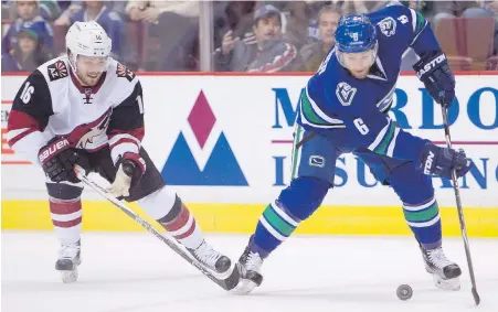  ??  ?? Canucks defenceman Yannick Weber fights for the puck with Coyotes centre Max Domi during first-period action at Rogers Arena in Vancouver on Monday night.