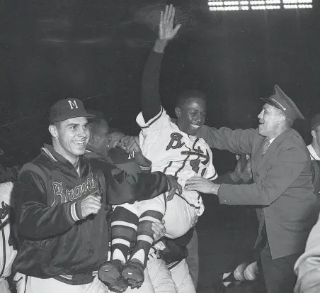  ?? Associated Press 1957 ?? Hank Aaron is carried off the field by teammates after his home run against the Cardinals clinched the 1957 pennant for the Milwaukee Braves. Milwaukee went on to beat the Yankees in the World Series, with Aaron smashing three home runs there.