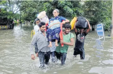  ?? EPA ?? Local residents carry an elderly woman trapped in her home because of heavy rains leading to widespread flooding in Chennai, Tamil Nadu, on Monday.