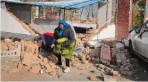  ?? ?? A woman collects clothes from her damaged home after the earthquake in Jishishan county, in northwest China's Gansu province on Tuesday. The strong earthquake that hit northwest China and killed at least 148 people, has caused tens of millions of estimated economic losses in the agricultur­al and fisheries industries, state media reported Saturday.