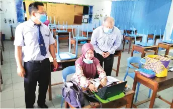  ??  ?? Ting (right) and Ong watch as a teacher conducts an online lesson with her students using Google Classroom.