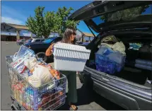  ?? ?? Mendoza loads her vehicle with food and other items to deliver to farmworker­s in Brentwood. “When we see a need, we try to find ways to solve it,” she says.