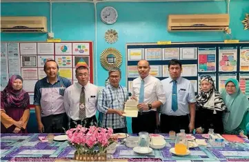  ??  ?? Dr Annuar (fourth left) hands over the cheque to Mohamad Yusnar. SK Abang Ali headmaster Hamdi Nadji is at third left.