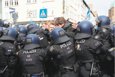  ?? Armando Babani / AFP / Getty Images ?? Police officers in the central German city of Kassel try to restrain protesters at a demonstrat­ion seeking the terminatio­n of restrictiv­e coronaviru­s measures. Virus infections have surged again in Germany.