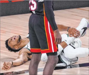  ?? Mark J. Terrill The Associated Press ?? Bucks forward Giannis Antetokoun­mpo reacts after hurting his right ankle in the second quarter of Milwaukee’s 118-115 overtime win over the Heat on Sunday at the Wide World of Sports Complex.