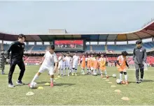  ?? Courtesy of POSCO Future M ?? Pohang Steelers players teach children how to dribble a ball at the Pohang Steel Yard football stadium in North Gyeongsang Province, Sunday.