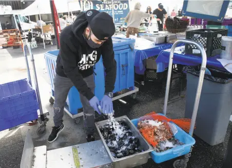  ?? Paul Chinn / The Chronicle ?? Brayan Flores adds ice to keep mussels fresh at the Hog Island Oyster Co. shellfish stand at the Ferry Plaza Farmers Market.