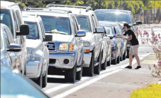  ?? Matt York The Associated Press ?? People line up to get tested for COVID-19 at a drive-thru testing site Saturday in Phoenix.