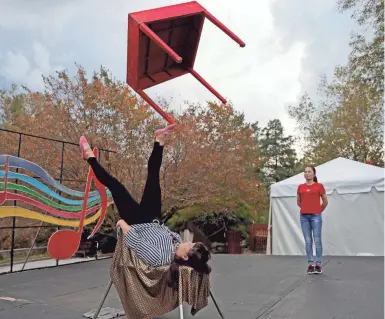  ?? MIKE DESISTI / MILWAUKEE JOURNAL SENTINEL ?? Zhao Xiaoli, a foot juggler at China Lights: Panda-Mania lantern festival at Boerner Botanical Gardens, practices juggling a table while Chow Jie, a Chinese yo-yo performer, looks on. More photos and a video at JSOnline.com