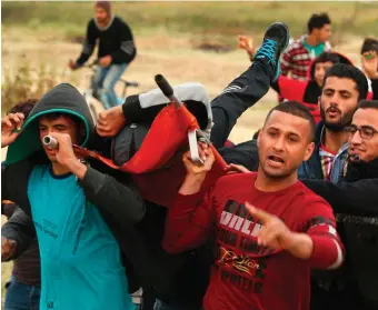  ?? Photo: Getty Images ?? Palestinia­n protesters carry an injured comrade during clashes with Israeli forces following a protest along the border with Israel, east of Gaza City yesterday.