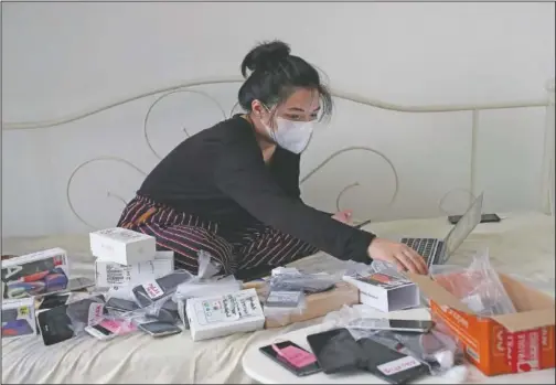  ?? (AP/Tatan Syuflana) ?? Indonesian journalist Ghina Ghaliya packs used mobile phones before shipping them to underprivi­leged children who lack internet access to study online at her apartment in Tangerang, Indonesia.