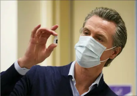  ?? JAE C. HONG — THE ASSOCIATED PRESS FILE ?? In this Dec. 14, 2020, file photo, California Gov. Gavin Newsom holds up a vial of the Pfizer-BioNTech COVID-19 vaccine at Kaiser Permanente Los Angeles Medical Center in Los Angeles. With frustratio­n rising over the slow rollout of the vaccine, state leaders and other politician­s are turning up the pressure, improvisin­g and seeking to bend the rules to get shots in arms more quickly.