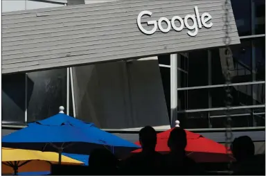 ?? (AP) ?? People walk by a Google sign on the company’s campus in Mountain View, Calif. Google is among companies delaying sending workers back to the office.