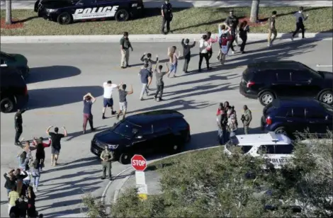  ?? MIKE STOCKER — SOUTH FLORIDA SUN-SENTINEL VIA AP ?? In this photo, students from Marjory Stoneman Douglas High School in Parkland, Fla., hold their hands in the air as they are evacuated by police after a shooter opened fire on the campus. The mass shooting which killed 17 students and staff, and sparked nationwide student-led marches for gun control — was the top news story of 2018, according to The Associated Press’ annual poll of U.S. editors and news directors.