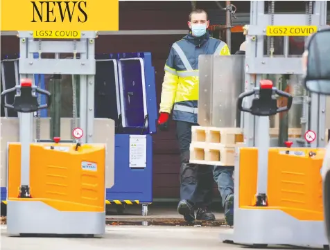  ?? OLIVIER MATTHYS/THE ASSOCIATED PRESS ?? An employee works with containers of dry ice at a Pfizer plant in Belgium. The company will be slowing vaccine shipments in the next four weeks.