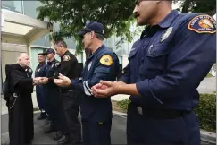  ?? ?? The Rev. Richard Hire blesses the hands of first responders as part of National Emergency Medical Services Week in Lynwood on Tuesday. Each person was given a medallion of Saint Michael, patron saint of first responders.