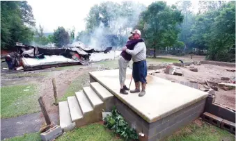  ??  ?? Jimmy Scott gets a hug from Anna May Watson, left, as they clean up from severe flooding in White Sulphur Springs, W. Va., on Friday. Scott lost his home to the flood and a fire that consumed his and the homes of several relatives.
