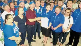  ??  ?? Welcome aboard: Tangau (centre in red shirt) receiving a party membership applicatio­n from former beauty queen Botiza Disimon, Leiking’s staunch supporter at the last general election.