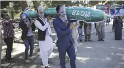  ??  ?? KABUL: Men from the Solidarity Party of Afghanista­n wear masks of President Trump, President Ghani and Dr. Abdullah, carrying a hand made model of the “Mother of all bombs” during a demonstrat­ion, against the US government. — AP