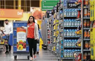  ?? Associated Press photos ?? Laila Ummelaila, a personal shopper at the Walmart in Old Bridge, N.J., pulls a cart loaded with bins as she shops for online customers. She says she enjoys her new responsibi­lities.