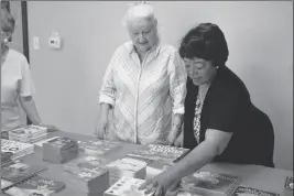  ??  ?? ROCHELLE THOMPSON (LEFT) AND RUTH BROCKINGTO­N LOOK THROUGH that they helped the Easterseal­s Blake Foundation buy. some of the books